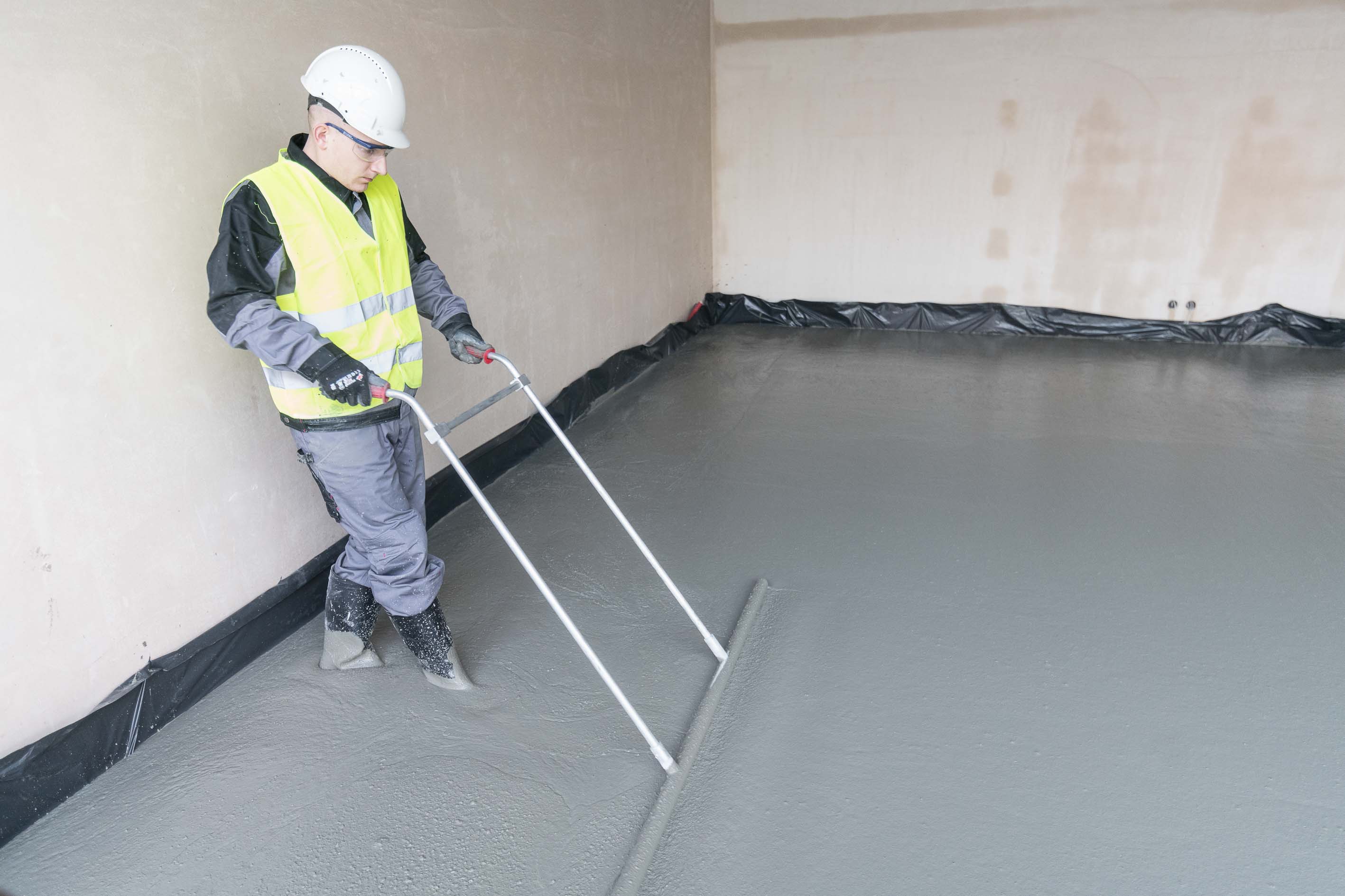 Construction worker laying self-levelling screed